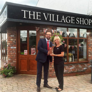 Shop Manager Julie accepts a community shop award from Palmer and Harvey.