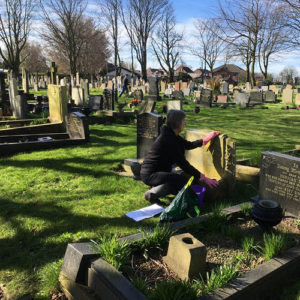 Volunteer cleans headstone as part of the Gravetending Scheme service.