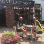 Cyclists enjoy the sun and refreshments in the shops's outdoor cafe area.