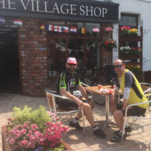 Cyclists enjoy the sun and refreshments in the shops's outdoor cafe area.