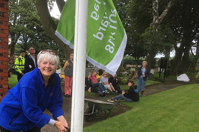 Chair Mandy Eccles proudly raises the 2017-2018 Green Flag - July 2017.